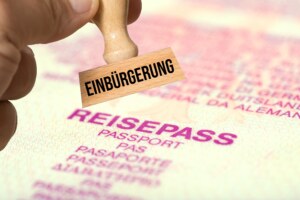 Das Bild zeigt einen Einbürgerungsstempel und im Hintergrund einen Reisepass.